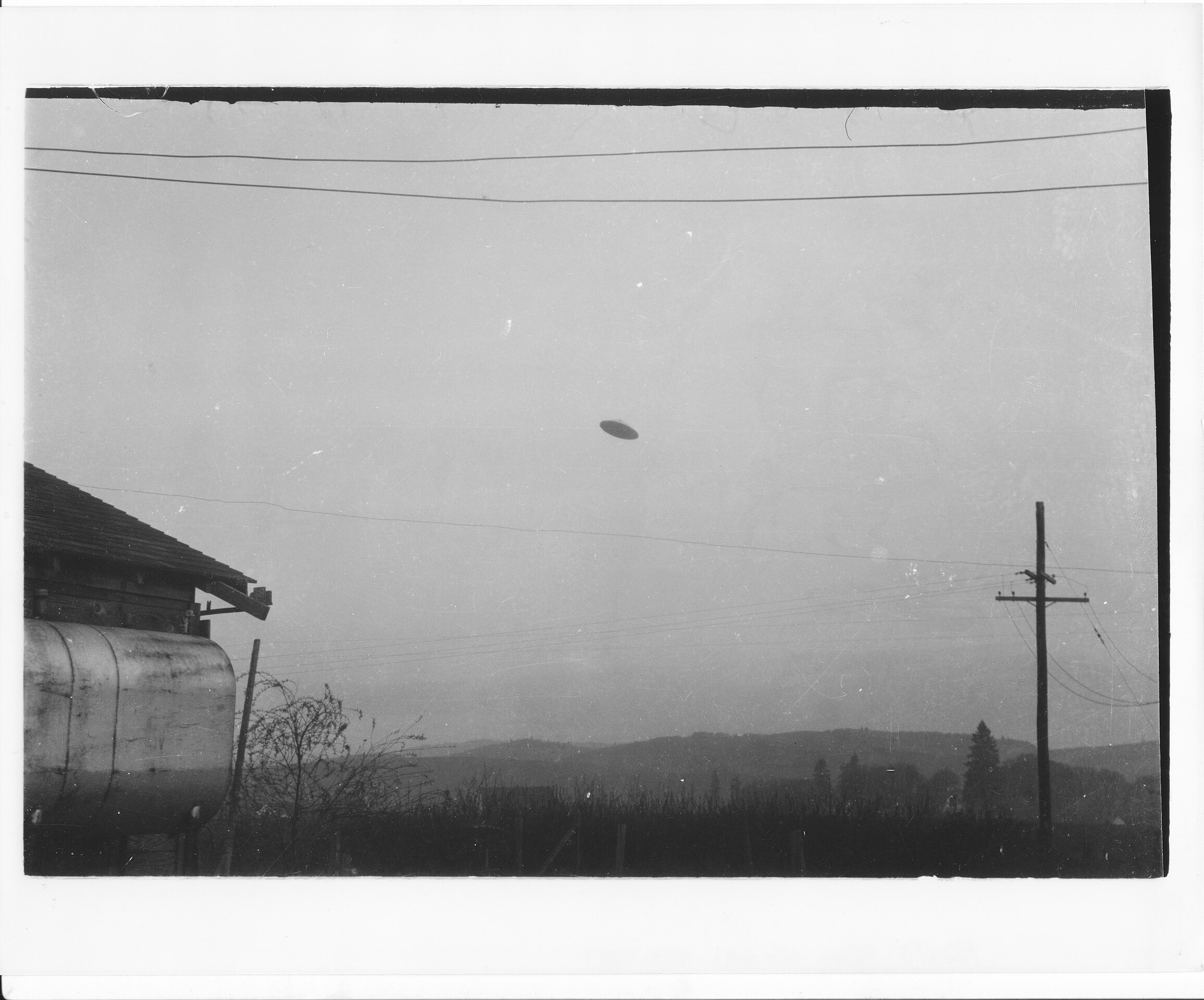 One of the McMinnville UFO photographs. Skeptics have concluded that the UFO was a small model suspended by wires or string from the power lines visible at the top of the photo.